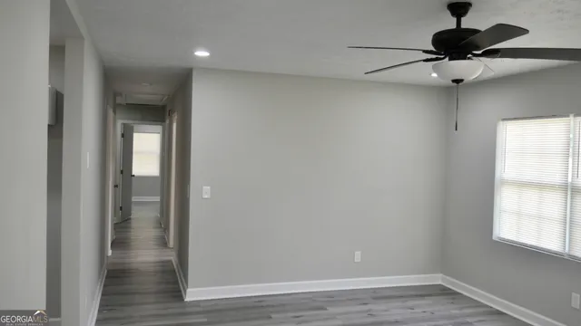 an empty room with wooden floor cabinet and windows
