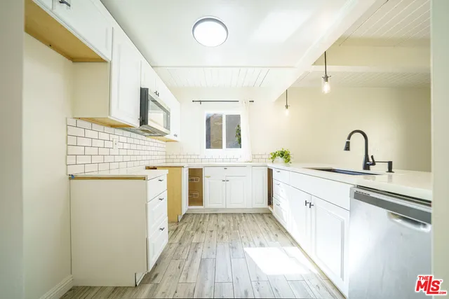 a large white kitchen with sink and wooden floor