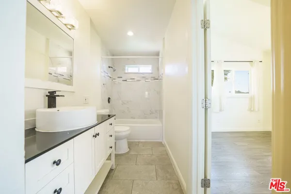 a bathroom with a double vanity sink toilet mirror and bathtub