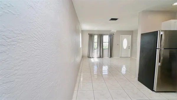 a view of a refrigerator in kitchen and an empty room