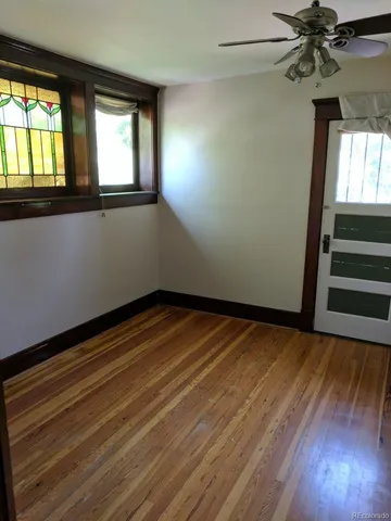 an empty room with wooden floor fan and windows