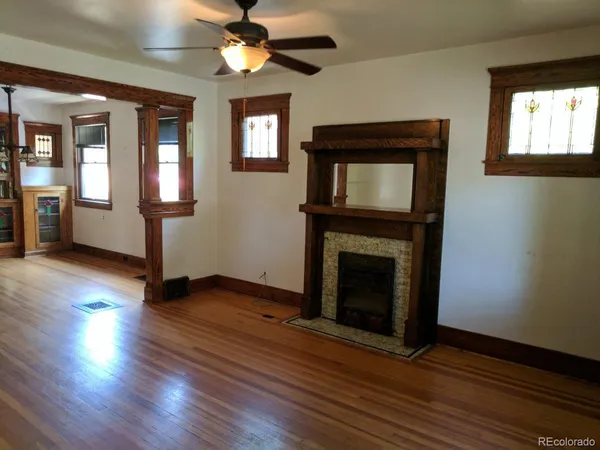 a view of an empty room with wooden floor and a fireplace