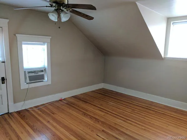 a view of an empty room with a window and wooden floor