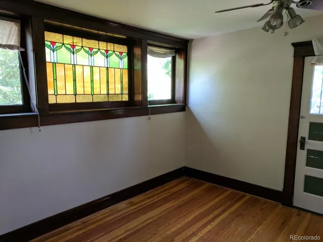 a view of an empty room with wooden floor and a window