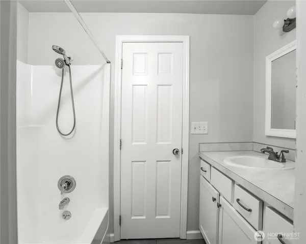 a bathroom with a granite countertop sink a mirror and shower
