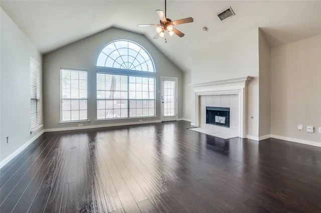 a view of an empty room with wooden floor fireplace and a window