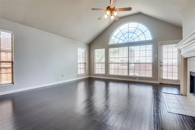 an empty room with wooden floor chandelier and windows