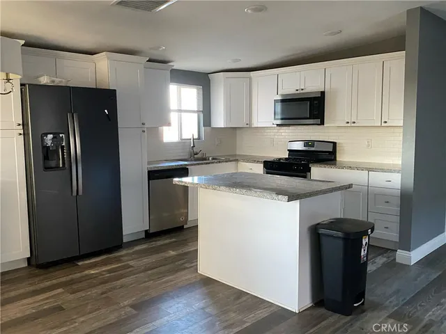 a kitchen with granite countertop white cabinets and stainless steel appliances