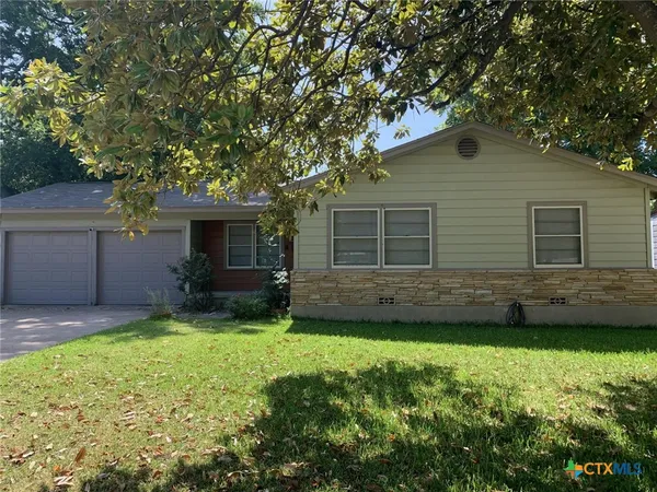 a view of a house with a yard and a large tree