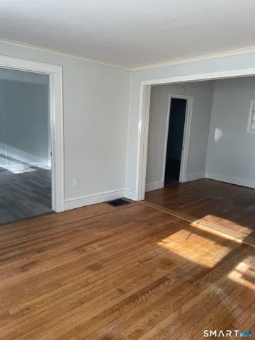 a view of an empty room with wooden floor and closet