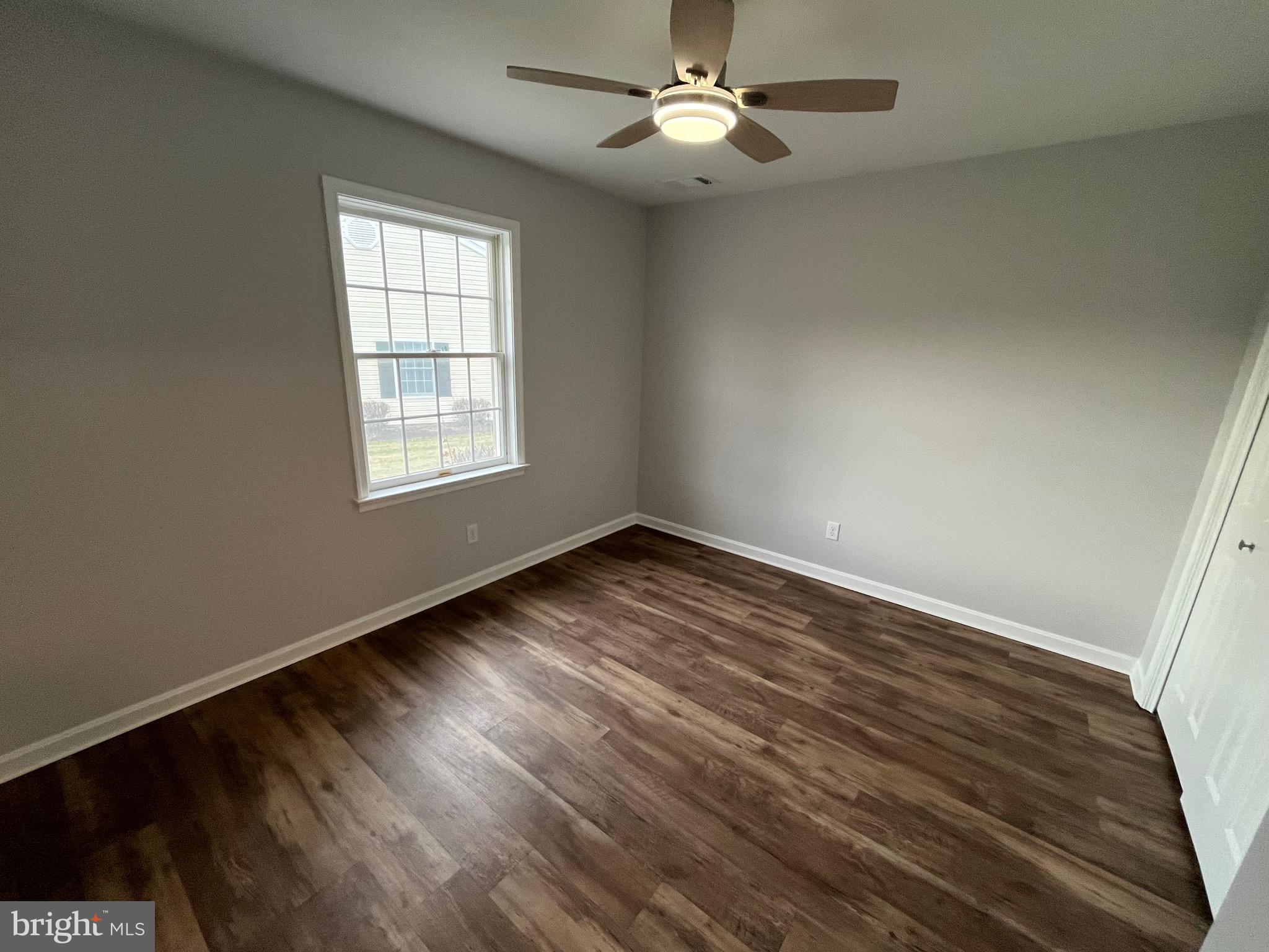 3077 Lakefield Road, Unit 3077 York, PA 17402 - Photo 14 of 33 an empty room with wooden floor chandelier fan and windows
