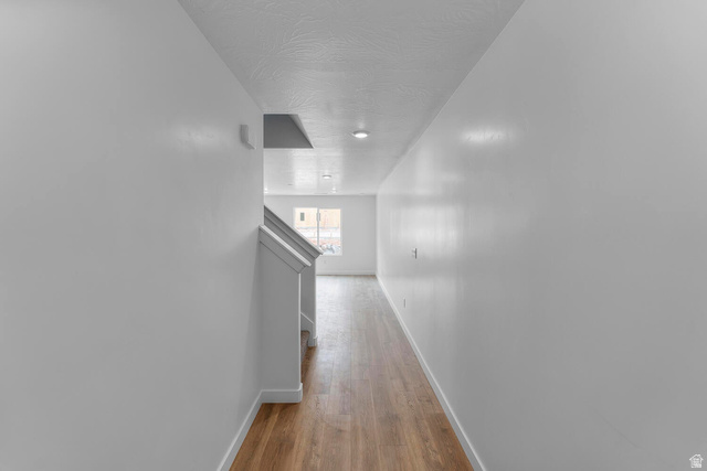 2133 Wolverine Way, Unit 2440 Washington, UT 84780 - Photo 3 of 39 Hallway featuring wood-finish flooring, white baseboards, recessed lighting, and a partial view of a staircase with white railings
