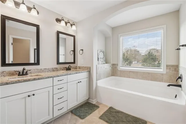 a bathroom with a tub a sink and a window