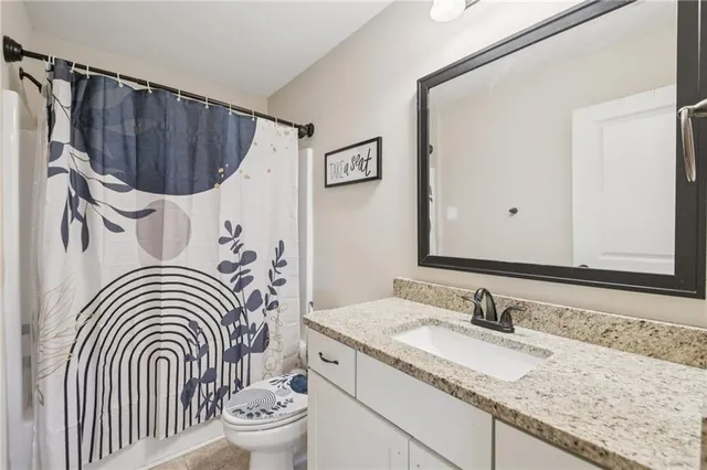 a bathroom with a granite countertop sink a toilet and a mirror