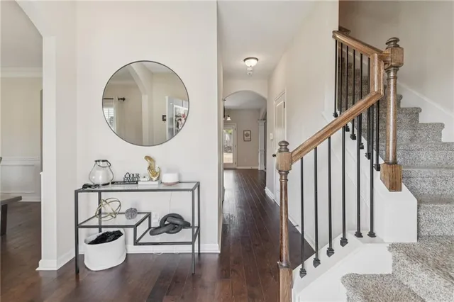 a view of a hallway with wooden floor couches and kitchen view