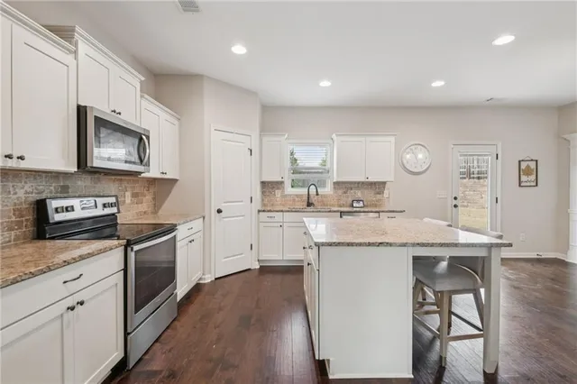 a kitchen with stainless steel appliances granite countertop a stove top oven a sink dishwasher and a refrigerator