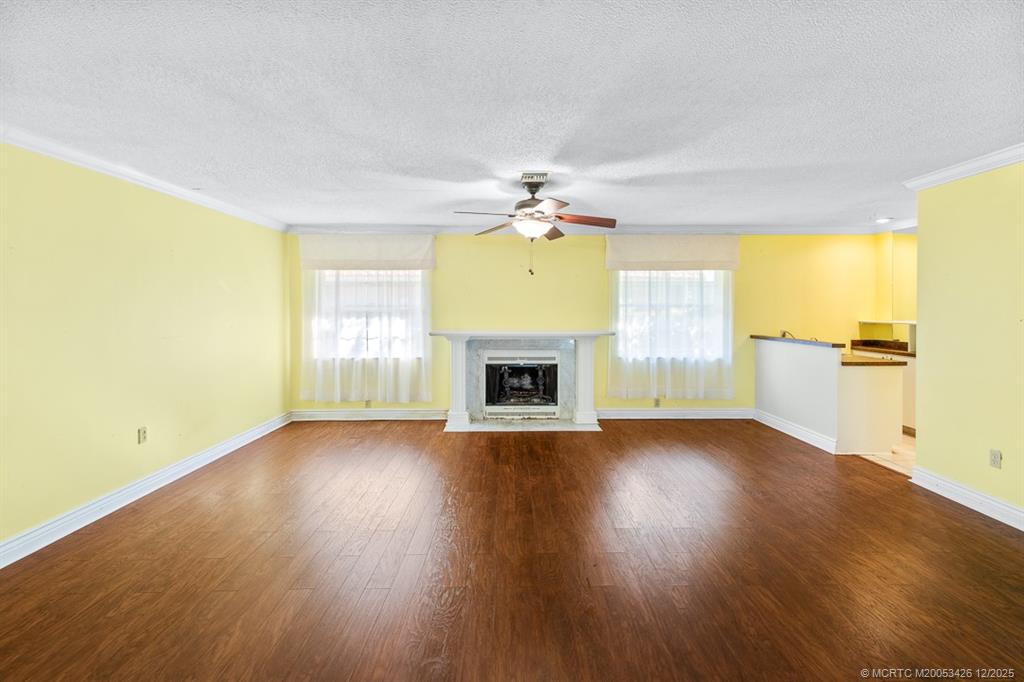 3181 Southeast Fairway West Stuart, FL 34997 - Photo 26 of 64 an empty room with a fireplace and wooden floor