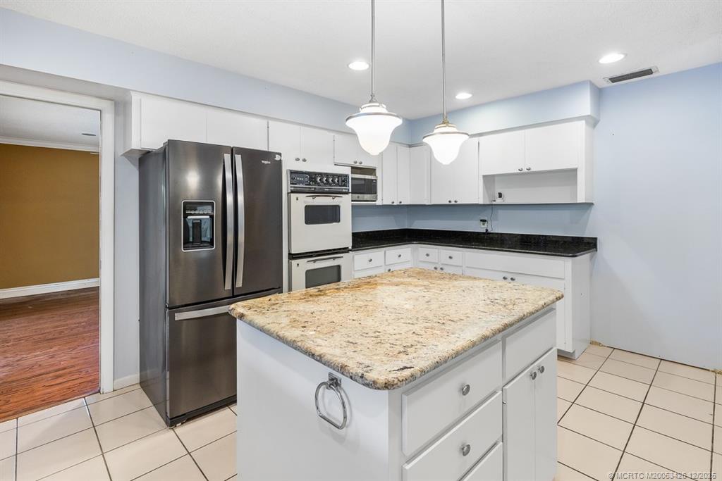 3181 Southeast Fairway West Stuart, FL 34997 - Photo 30 of 64 a kitchen with granite countertop a refrigerator and microwave