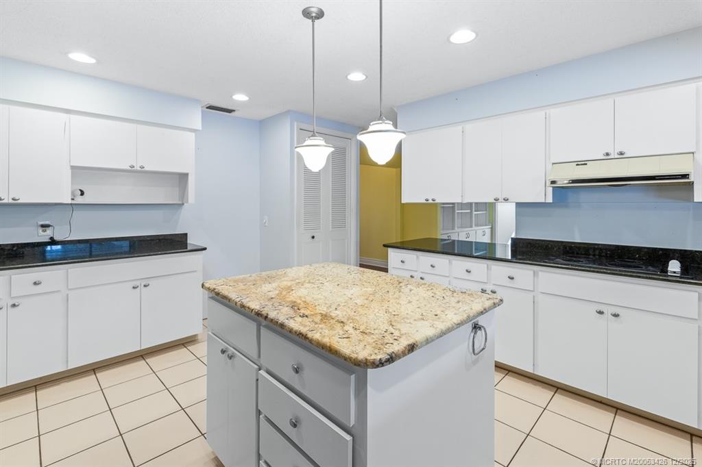 3181 Southeast Fairway West Stuart, FL 34997 - Photo 34 of 64 a kitchen with a sink dishwasher and white cabinets with wooden floor