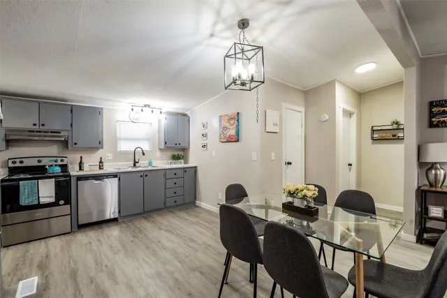 a kitchen with stainless steel appliances kitchen island granite countertop a dining table chairs and white cabinets