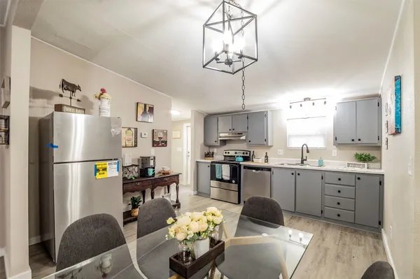 a kitchen with stainless steel appliances a refrigerator a sink a dining table and chairs