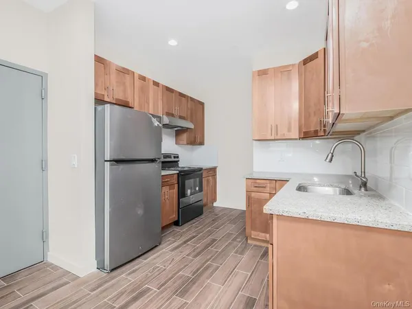 a kitchen with granite countertop stainless steel appliances a refrigerator a sink and cabinets