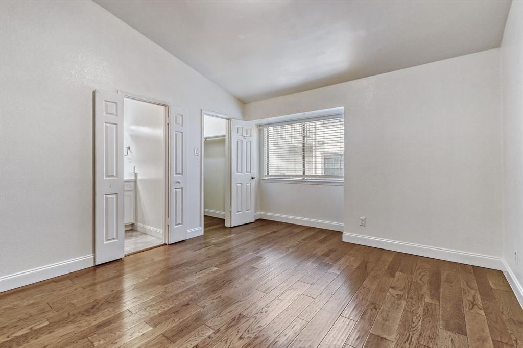 8750 Park Lane, Unit 142 Dallas, TX 75231 - Photo 11 of 17 Secondary bedroom with vaulted ceiling, a walk in closet, light wood floors, and ensuite bathroom