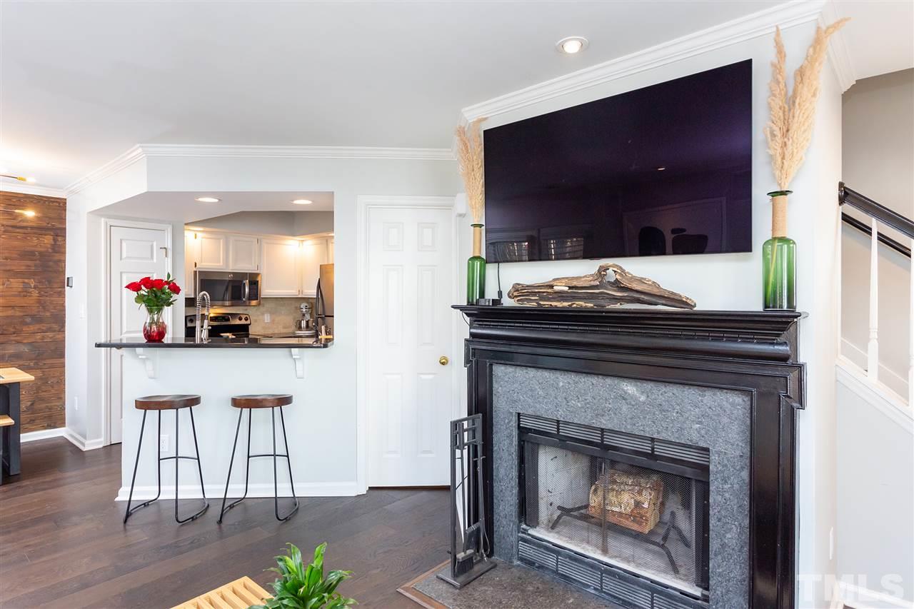 1462 Barton Pl Drive Raleigh, NC 27608 - Photo 13 of 25 a kitchen with a fireplace a flat screen tv and chairs