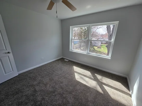 an empty room with windows and fan