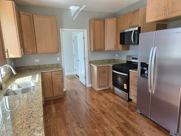 a kitchen with granite countertop a refrigerator stove and sink