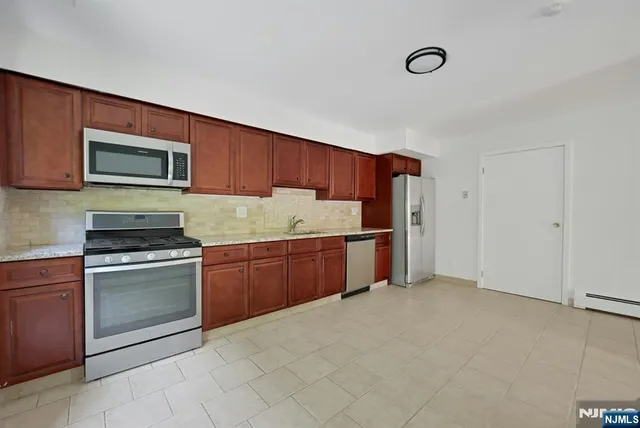 a kitchen with granite countertop a refrigerator and a stove top oven