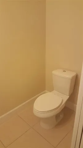 a white toilet sitting next to a white wall