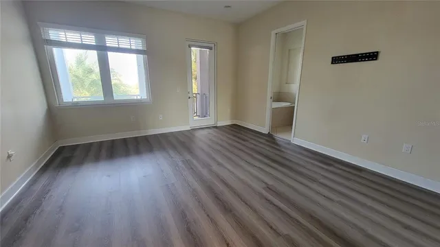 an empty room with wooden floor and windows