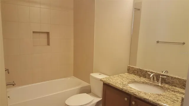 a bathroom with a granite countertop toilet and a sink