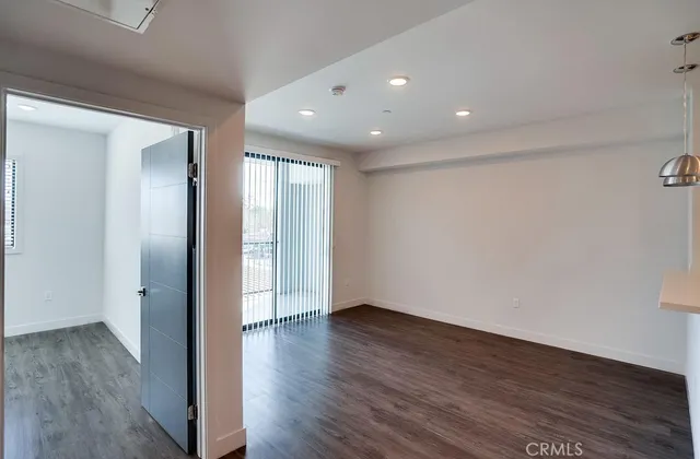 a view of an empty room with wooden floor and closet