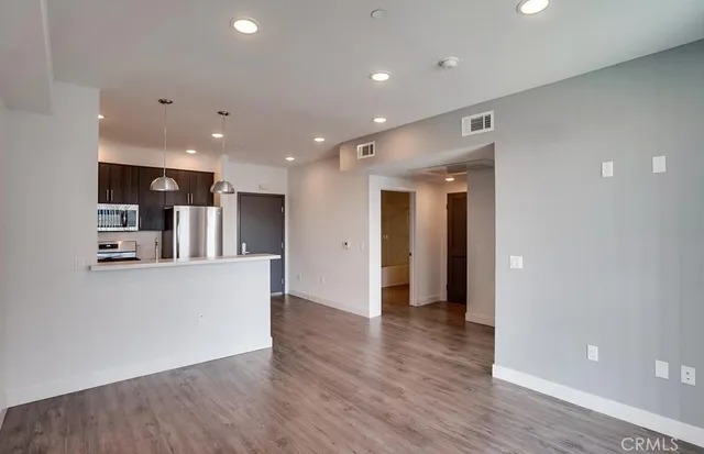 a view of kitchen with kitchen island wooden floor center island and stainless steel appliances