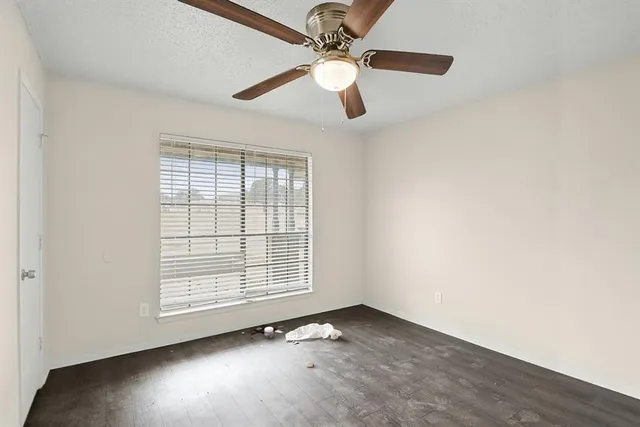 an empty room with windows and fan