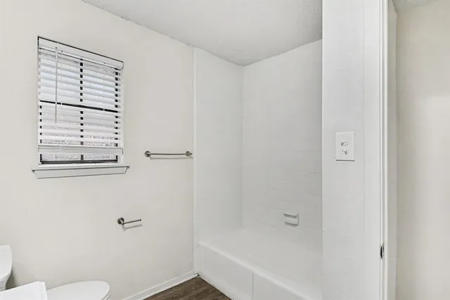 a bathroom with a granite countertop bathtub shower and toilet