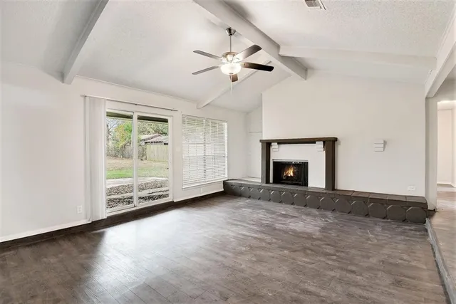 an empty room with windows fireplace and a ceiling fan