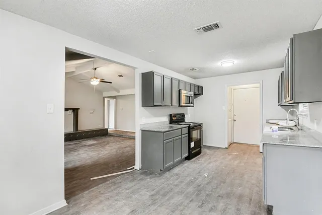 a view of a kitchen with a sink and dishwasher a stove top oven with wooden floor