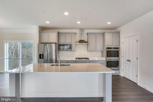a large kitchen with stainless steel appliances a large counter top and a refrigerator