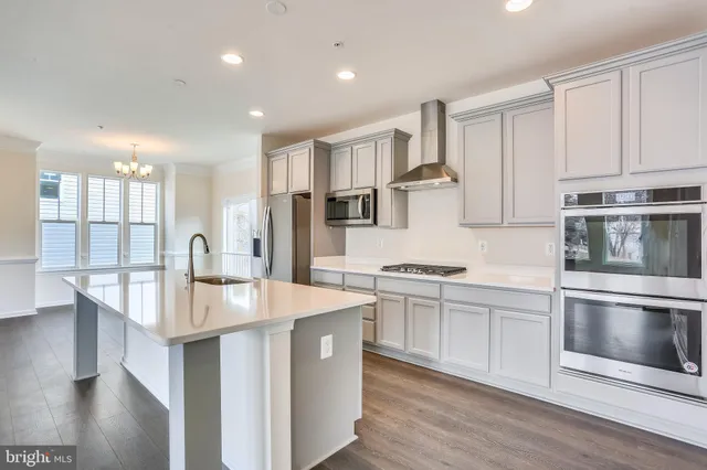 a kitchen with stainless steel appliances granite countertop a stove top oven a sink and white cabinets