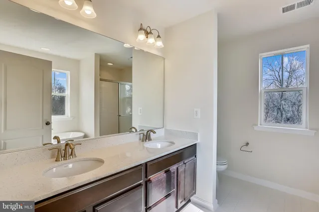 a bathroom with a sink double vanity granite tub and a mirror
