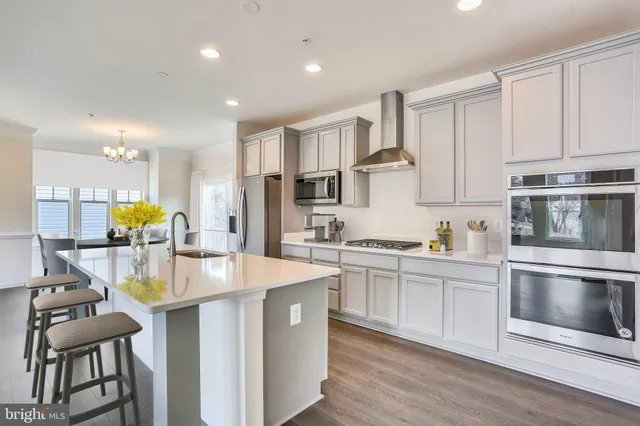 a kitchen with stainless steel appliances granite countertop a stove top oven a sink dishwasher and white cabinets with wooden floor