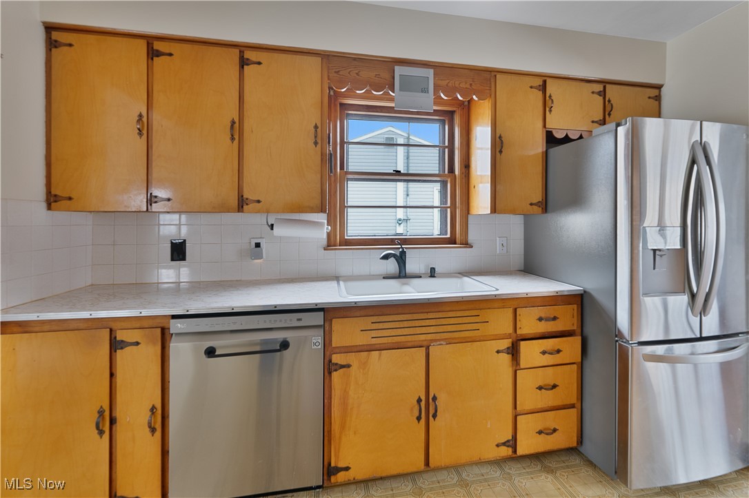 2702 Brunswick Road Youngstown, OH 44511 - Photo 8 of 18 Kitchen featuring backsplash, appliances with stainless steel finishes, light countertops, and a sink
