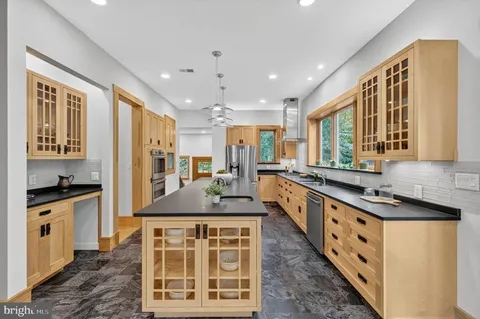 a large kitchen with stainless steel appliances granite countertop a sink a counter space and windows
