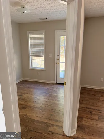 a view of an empty room with wooden floor and a window
