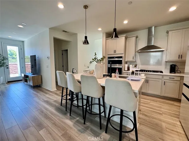 a large kitchen with cabinets wooden floor white stainless steel appliances and dining table