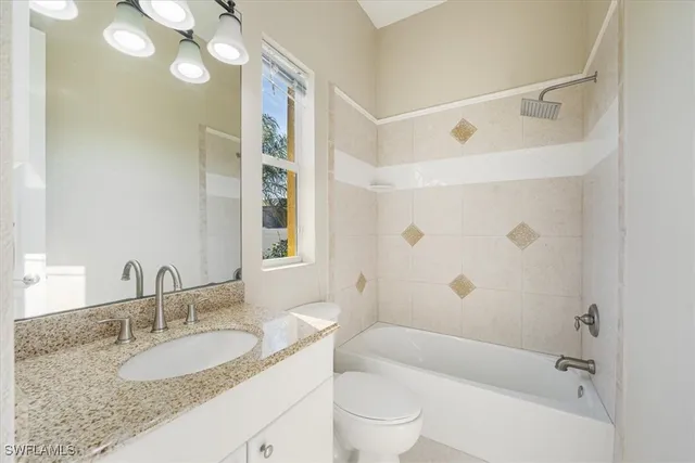 a bathroom with a granite countertop sink a toilet a mirror a bathtub and shower