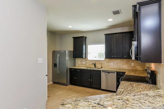 a kitchen with a sink a refrigerator and cabinets